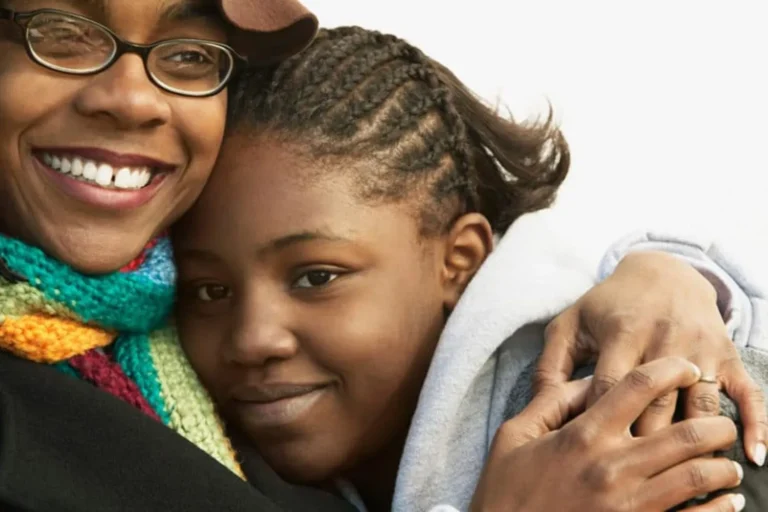 Smiling woman embraces a young girl in a close, affectionate moment of love and support.