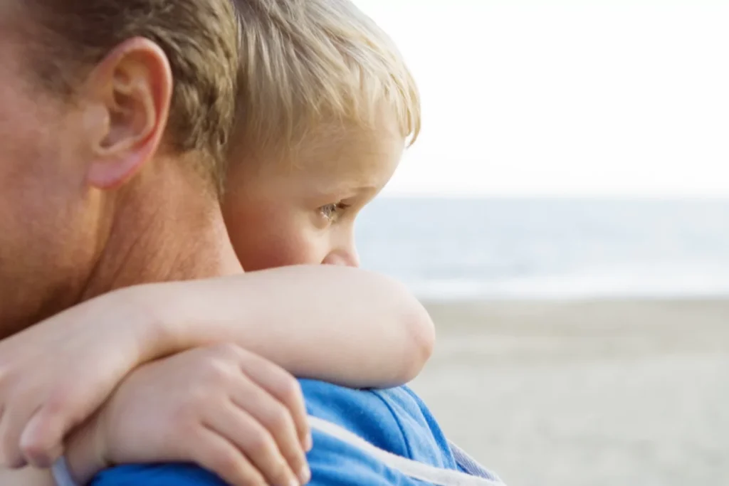 Young child resting on an adult’s shoulder in a quiet moment of comfort and emotional security.