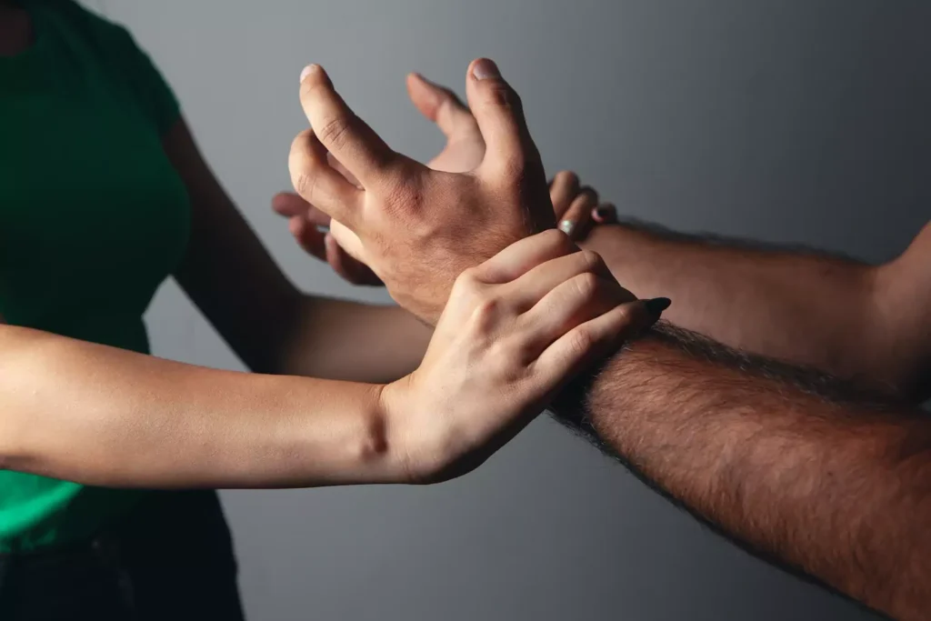 Photo of a woman's arms holding off a man's arms in a struggle, indicating sexual abuse in marriage.